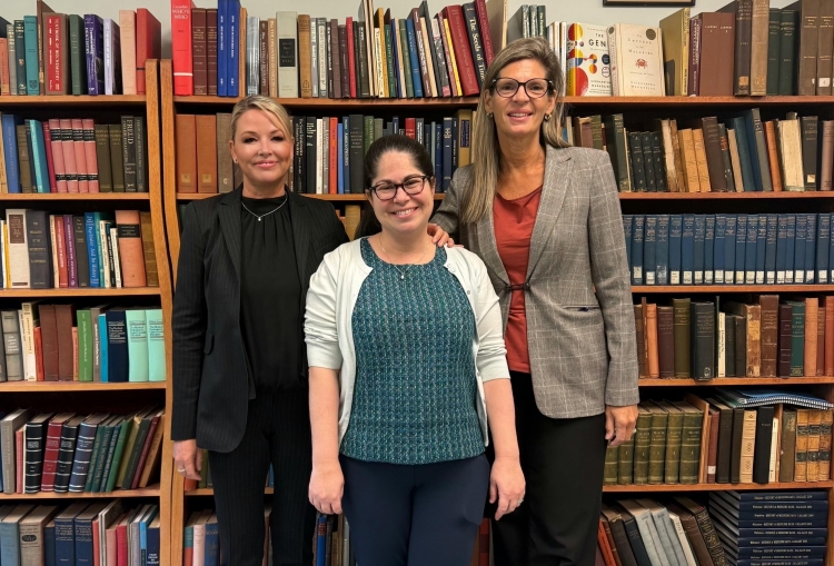 Dr. Deborah Doroshow, Dr. Shelley McKellar, and another person stand smiling in front of full bookshelves